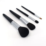 Angled view of four Chikuhodo makeup brushes arranged diagonally on a white surface, featuring sleek black handles, silver ferrules, and soft bristles in varying shapes for face and eye application.