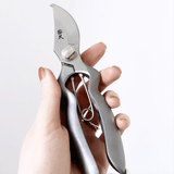 Hand holding Hidehisa stainless garden pruners – precision Japanese shears with curved blade and ergonomic grip