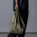 ISA Monyo Yui furoshiki in Rikyu green styled as a hand-carried bag, traditional Japanese wrapping cloth for everyday use.