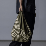 ISA Monyo Yui furoshiki in Rikyu green styled as a hand-carried bag, traditional Japanese wrapping cloth for everyday use.