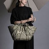 ISA Monyo Yui furoshiki in Rikyu green used as a large wrapped bag, traditional Japanese wrapping cloth for everyday and gift use.