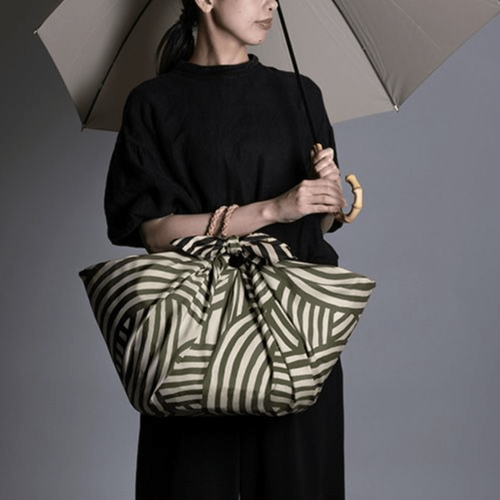 ISA Monyo Yui furoshiki in Rikyu green used as a large wrapped bag, traditional Japanese wrapping cloth for everyday and gift use.