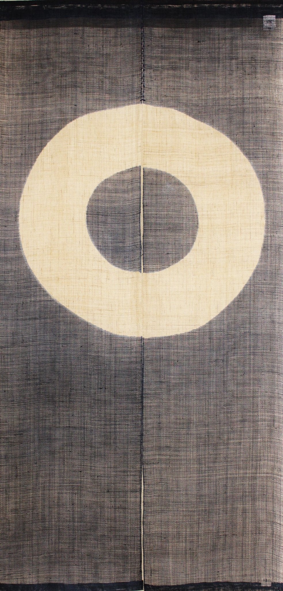 Close-up of Janome noren curtain featuring concentric circle motif in natural and charcoal tones, traditional Japanese fabric panel.