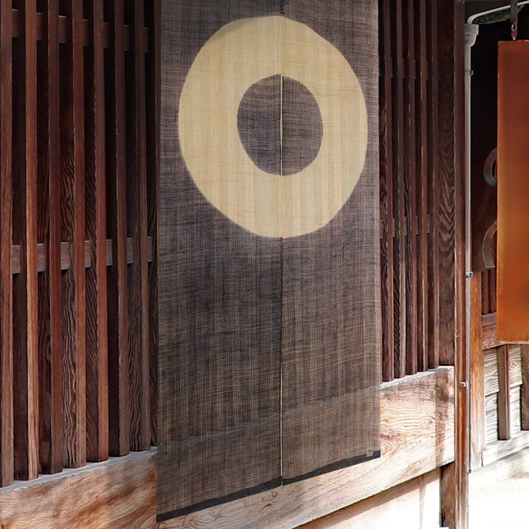 Janome noren curtain with concentric circle motif hanging in a traditional wooden Japanese entryway