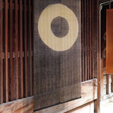Janome noren curtain with concentric circle motif hanging in a traditional wooden Japanese entryway