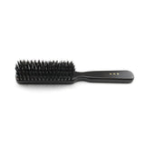 Side profile of a Kanaya medium-stiffness natural bristle hair brush, showcasing densely packed black bristles and a smooth black wooden handle with gold Japanese lettering, placed on a white background.