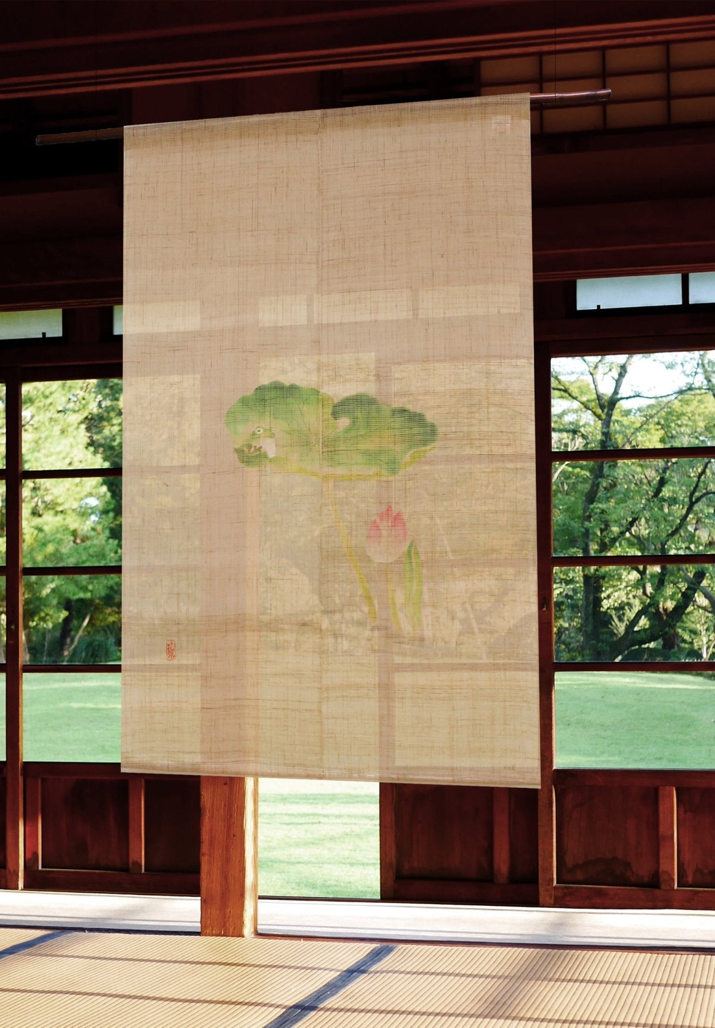 Lotus Pond noren curtain with frog and lotus design hanging in front of a sunlit Japanese window overlooking a garden.