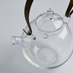 Close-up of the Manmaru glass teapot with a brass handle, showing the detailed spout, lid, and minimalist Japanese glass craftsmanship.
