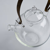 Close-up of the Manmaru glass teapot with a brass handle, showing the detailed spout, lid, and minimalist Japanese glass craftsmanship.