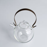 Top view of the Manmaru glass teapot with a sturdy brass handle, highlighting its minimalist Japanese craftsmanship and elegant round body.