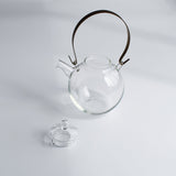 Manmaru glass teapot with a brass handle and its lid removed, showcasing its handcrafted Japanese design and minimalist aesthetic on a white background.