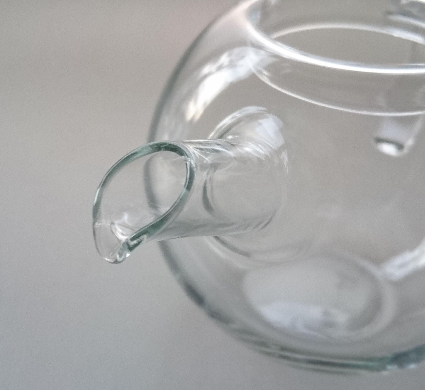 Detailed close-up of the Manmaru glass teapot spout, highlighting its elegant curved design and seamless borosilicate glass finish for smooth pouring.