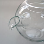 Detailed close-up of the Manmaru glass teapot spout, highlighting its elegant curved design and seamless borosilicate glass finish for smooth pouring.
