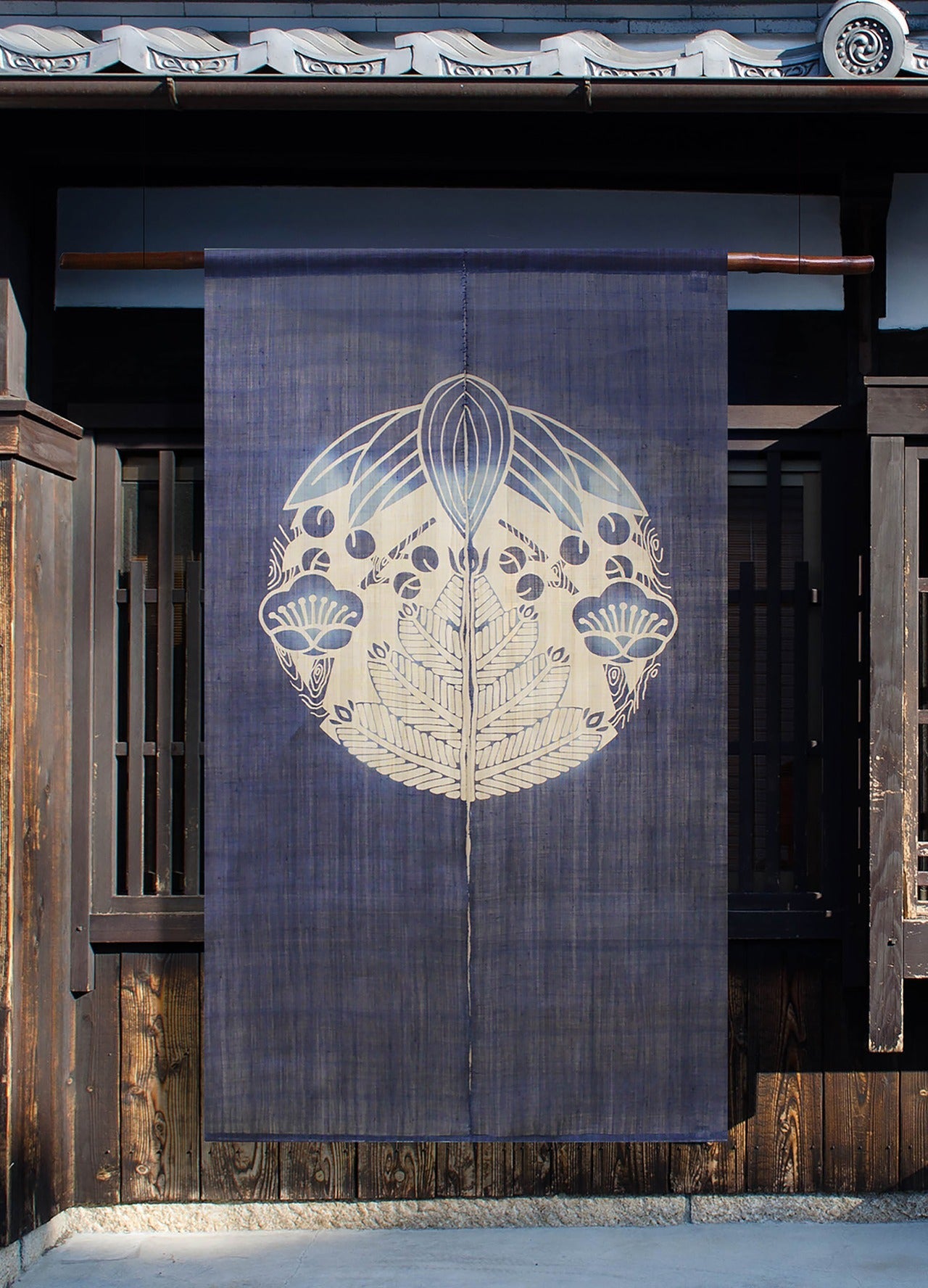 Shochikubai noren curtain in indigo with pine, bamboo, and plum motif hanging in a traditional Japanese doorway.
