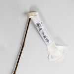 Traditional Japanese silk duster with a bamboo handle and white silk strips, shown with its paper wrapping featuring Japanese calligraphy.
