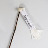 Traditional Japanese silk duster with a bamboo handle and white silk strips, shown with its paper wrapping featuring Japanese calligraphy.