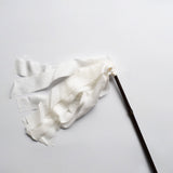 Japanese silk duster with flowing white silk strips and a dark bamboo handle, laid on a white background.